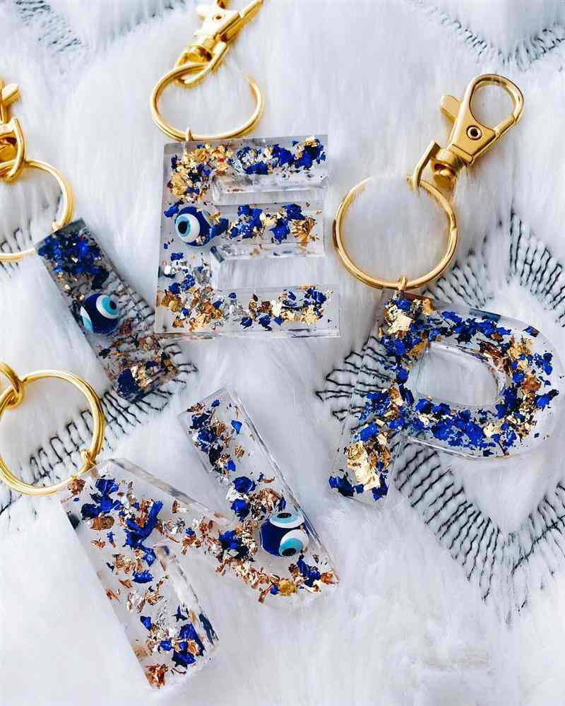 Chaveiros personalizados com letras e olho grego em resina azul e dourado